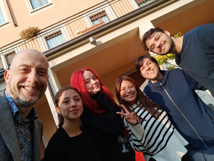 Foto di gruppo di sei persone sorridenti nel cortile della Casa di Brescia Bronzetti.