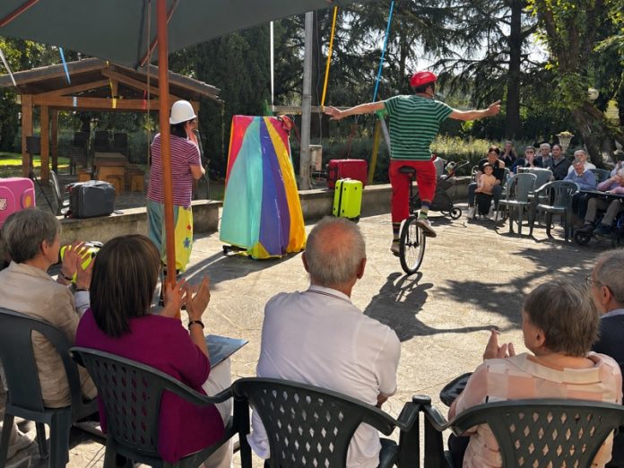 Due artisti, uno sul monociclo, si esibiscono davanti al pubblico nel giardino dell’Istituto Palazzolo.