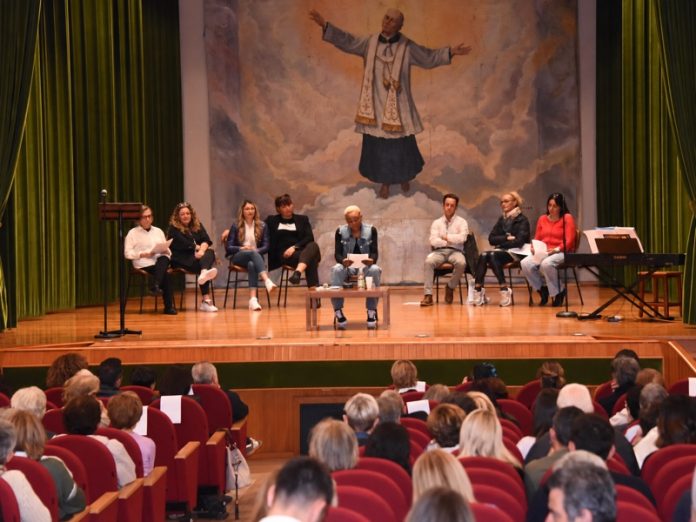 Lettura di testimonianze sul palco del teatro dell’Istituto Don Luigi Palazzolo durante la Settimana della Cultura.